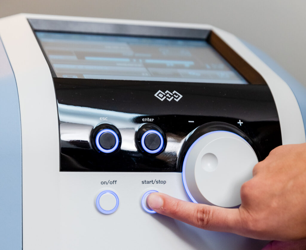 A close-up of a provider's hand using Emsella for pelvic floor therapy in Columbus, OH.