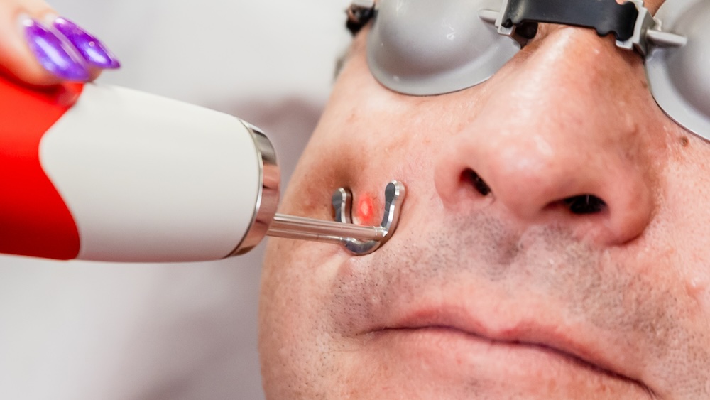 Person with laser pressed against his cheek as part of a personalized treatment for skin care in Columbus, OH